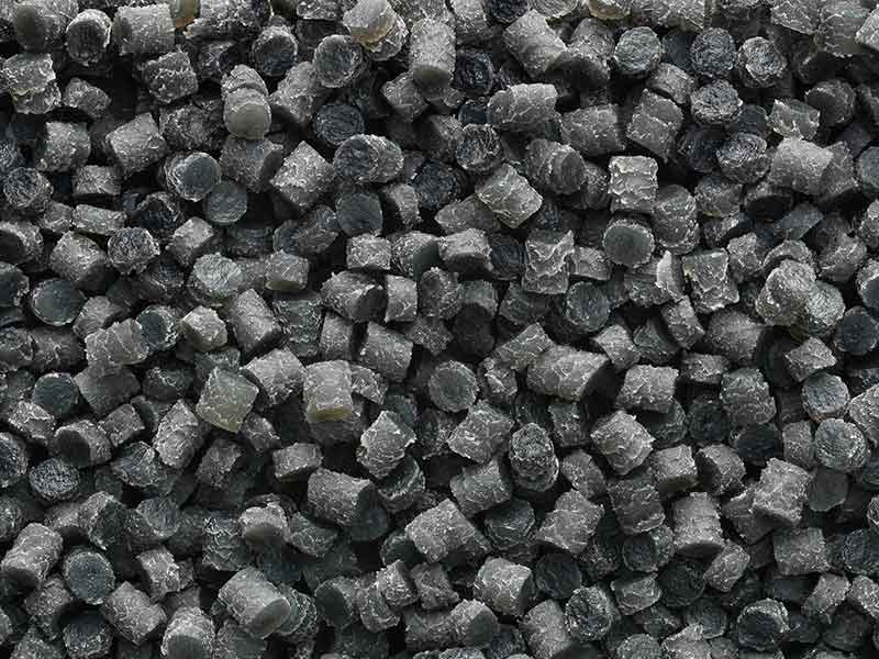 Pequeños pellets de color gris oscuro, procedentes de un proceso de preparación de compuestos de goma