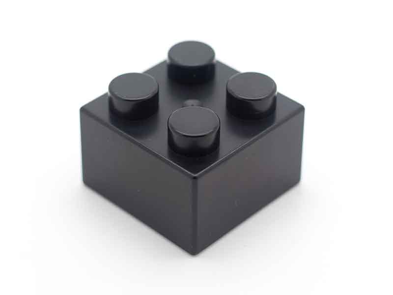Schwarzer Legostein als Beispiel für Masterbatch Compounder von BUSS